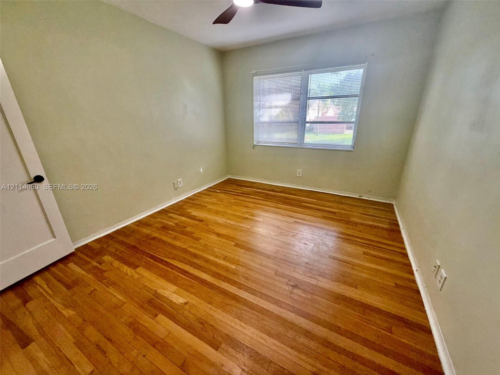 Interior space featuring wood-finish flooring, a multi-pane window, and an attached ceiling fan