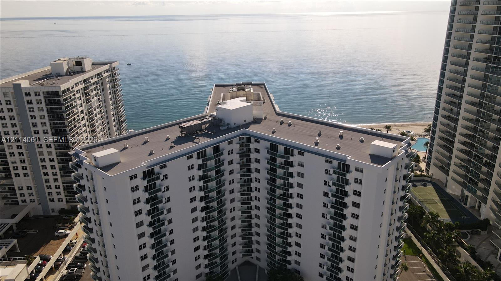 High-rise residential building featuring white exterior cladding, a multi-wing structural design, and private balconies with glass railings