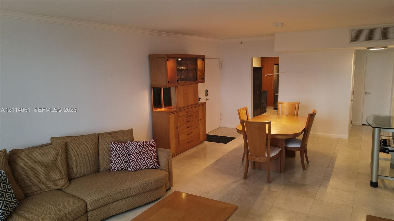 Open-concept interior featuring neutral tile flooring, recessed lighting, and a built-in wooden cabinetry unit