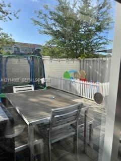 Rear patio area featuring stone-paver flooring, a perimeter concrete masonry unit wall, and white picket fencing