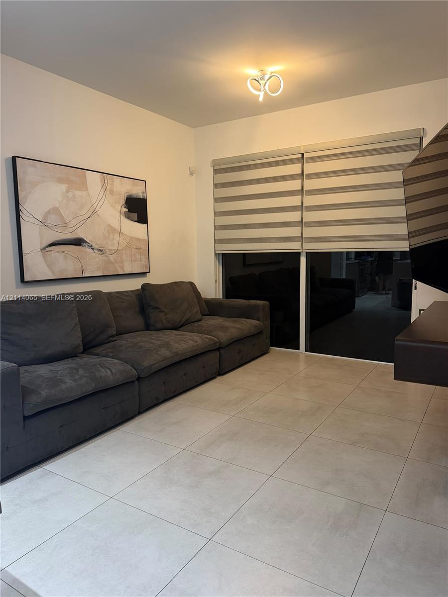 Large-format tile flooring, dual-layer privacy shades, and ceiling-mounted LED light fixture