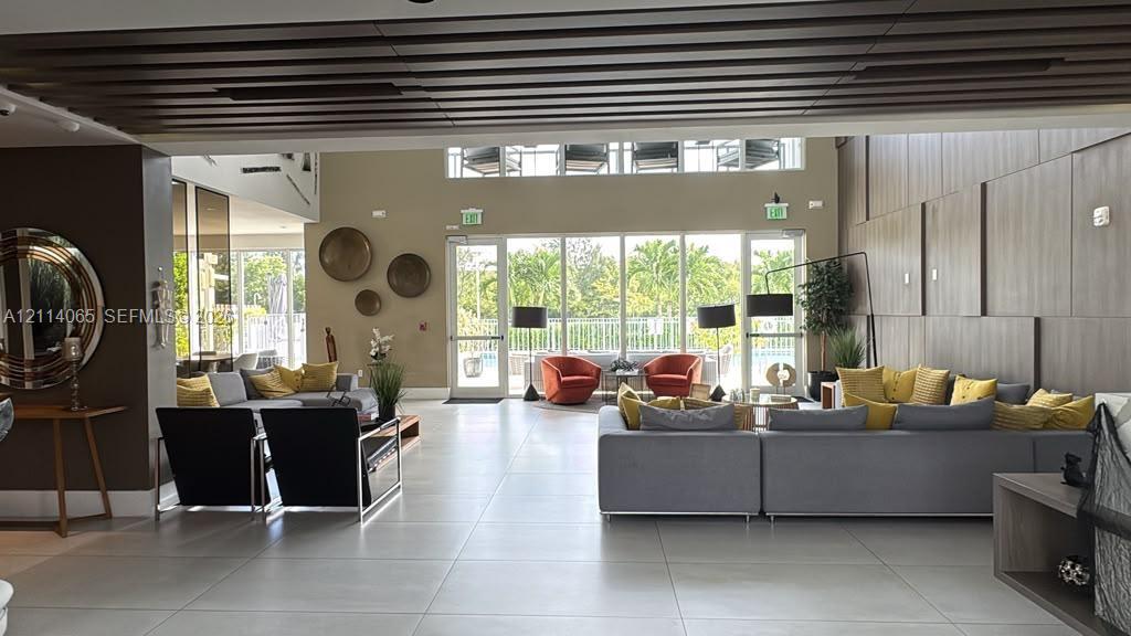 Open-concept interior featuring large-format tile flooring, slatted wood-finish ceiling detailing, expansive floor-to-ceiling glass windows, and vertical wood-panel wall cladding