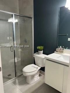 Glass-enclosed shower with tiled surround, white cabinet vanity with integrated sink, rectangular wall-mounted mirror, and neutral tile flooring