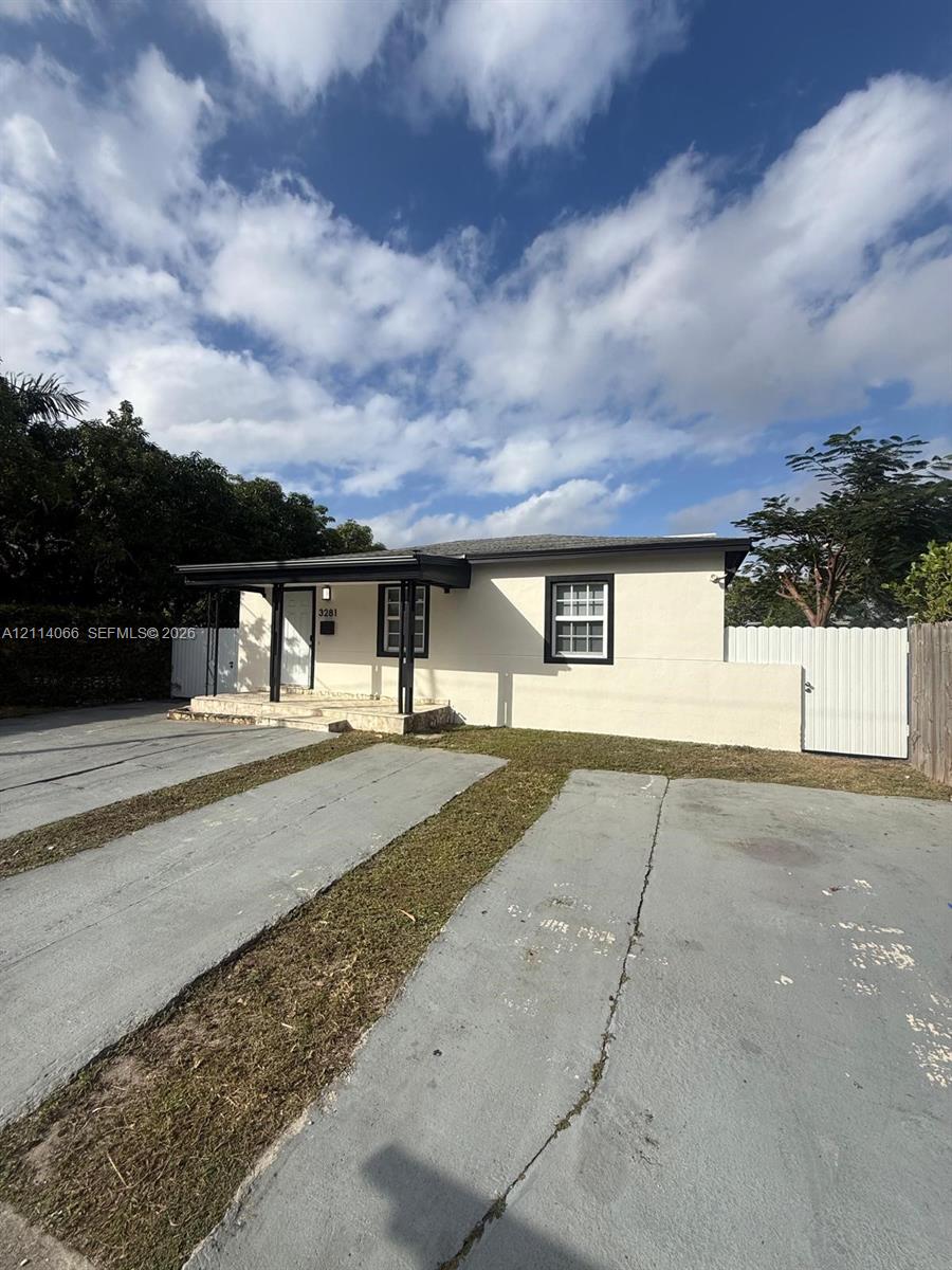 Exterior featuring a neutral stucco facade, a covered front porch with a stone-accented foundation, dual-pane windows with contrasting trim, and concrete driveway space