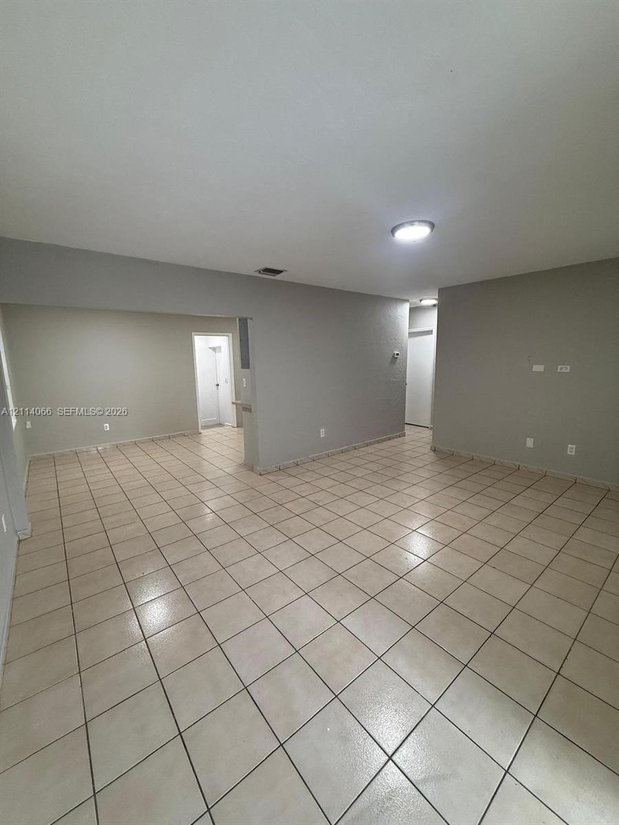 Neutral interior featuring large-format ceramic tile flooring and recessed ceiling lighting