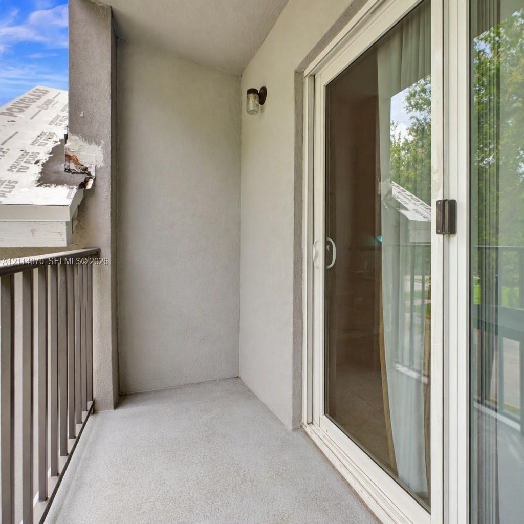 Private balcony featuring a concrete floor, metal railing, exterior wall-mounted light fixture, and double-pane sliding glass door