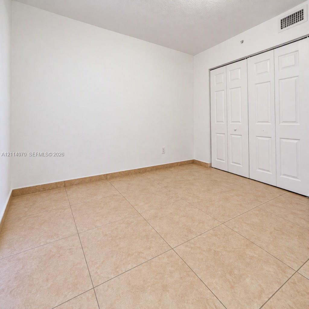 Neutral-toned tile flooring, white wall finish, and bi-fold closet doors