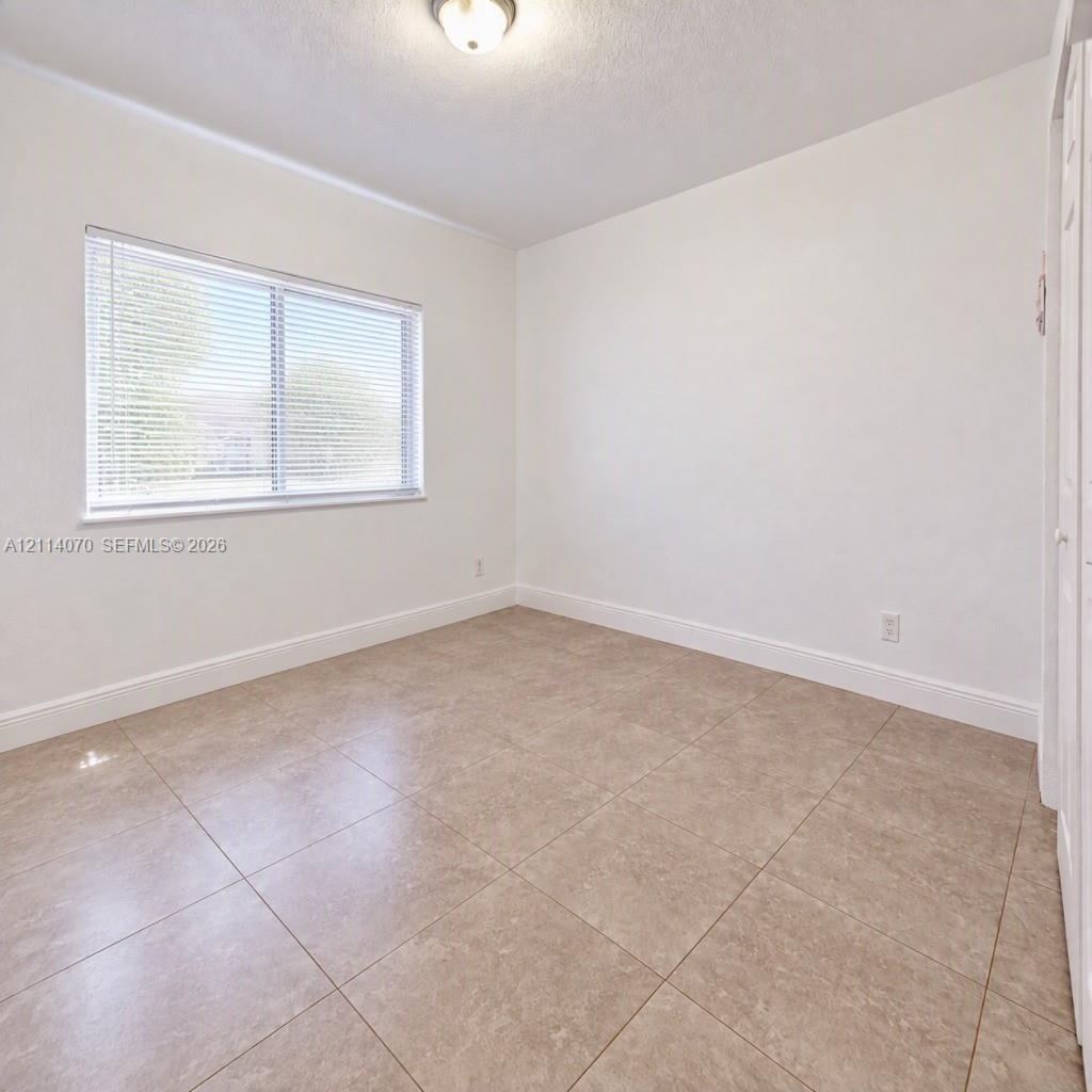 Neutral-toned ceramic tile flooring, crisp white wall finish, recessed overhead lighting, and dual-pane window with integrated blinds