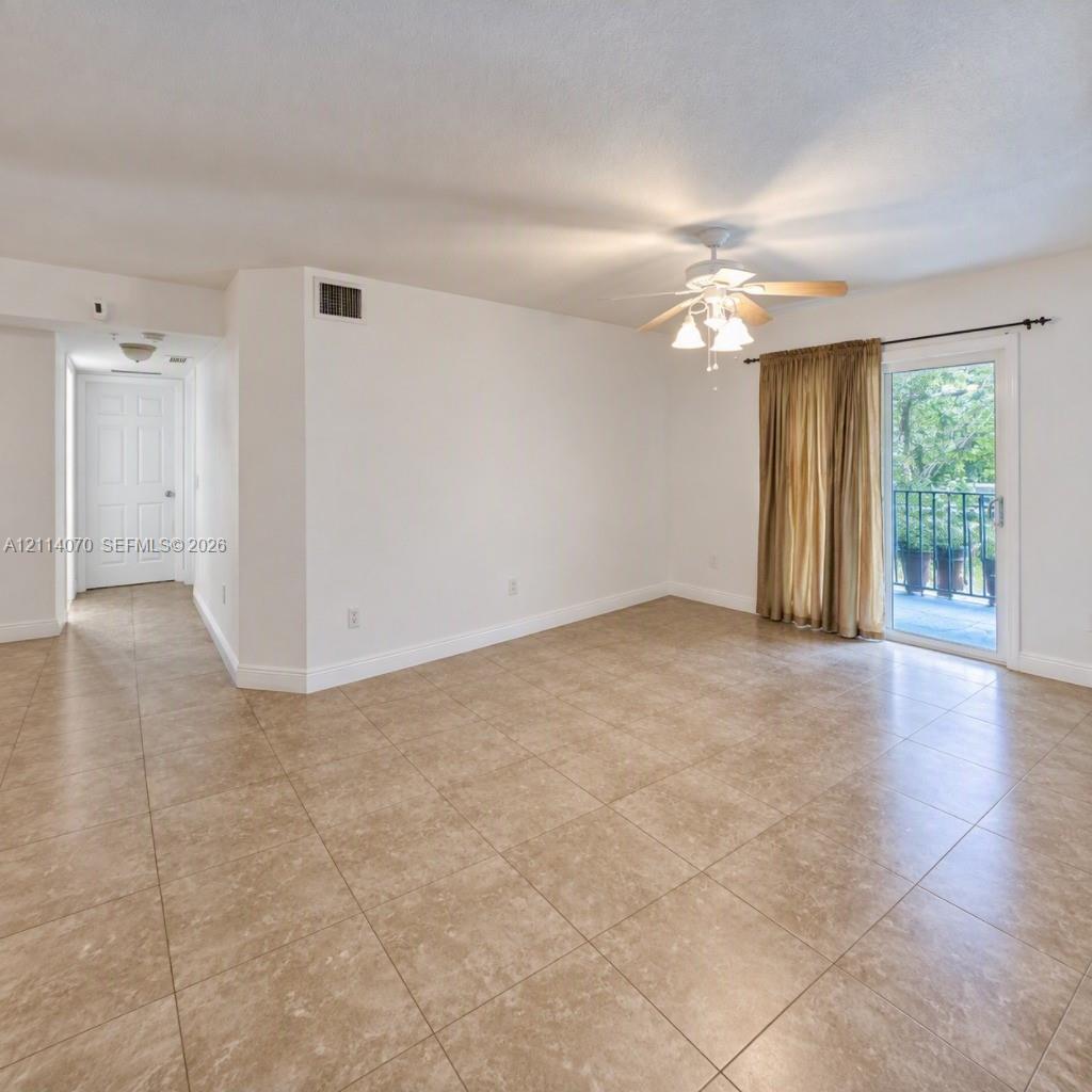 Interior space featuring large-format ceramic tile flooring, a multi-light ceiling fan, and sliding glass doors providing access to an outdoor balcony