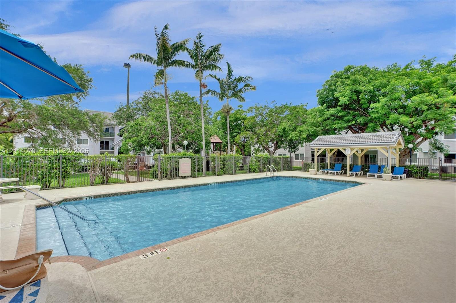 Outdoor swimming pool featuring a concrete deck, built-in metal handrails, and a covered pavilion structure