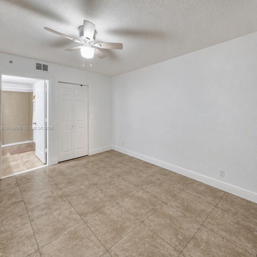 Interior space featuring large-format ceramic tile flooring, a multi-blade ceiling fan with integrated lighting, and a bi-fold closet door