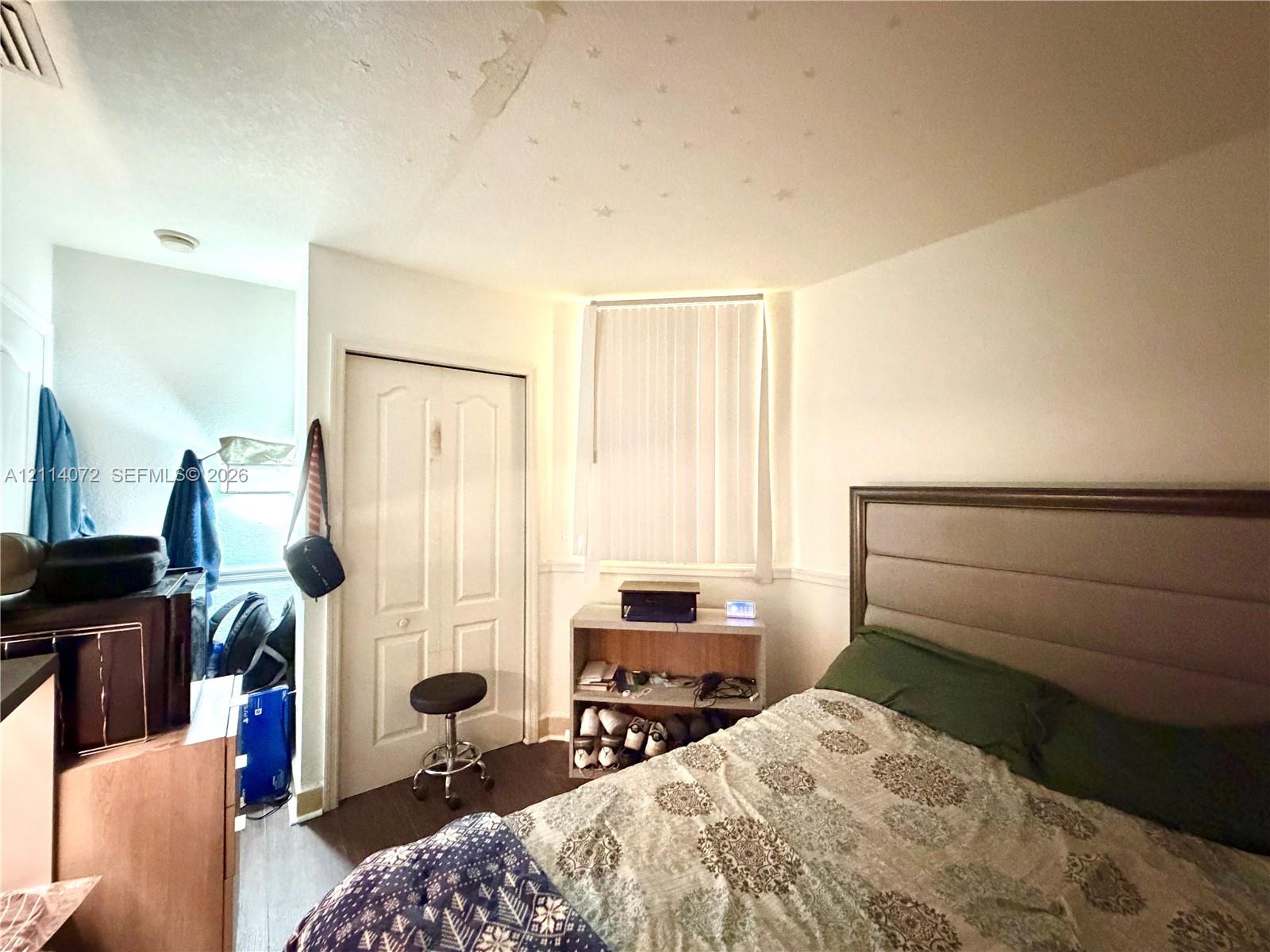 Room featuring wood-finish flooring, a double-door closet, a window with vertical blinds, and chair rail molding