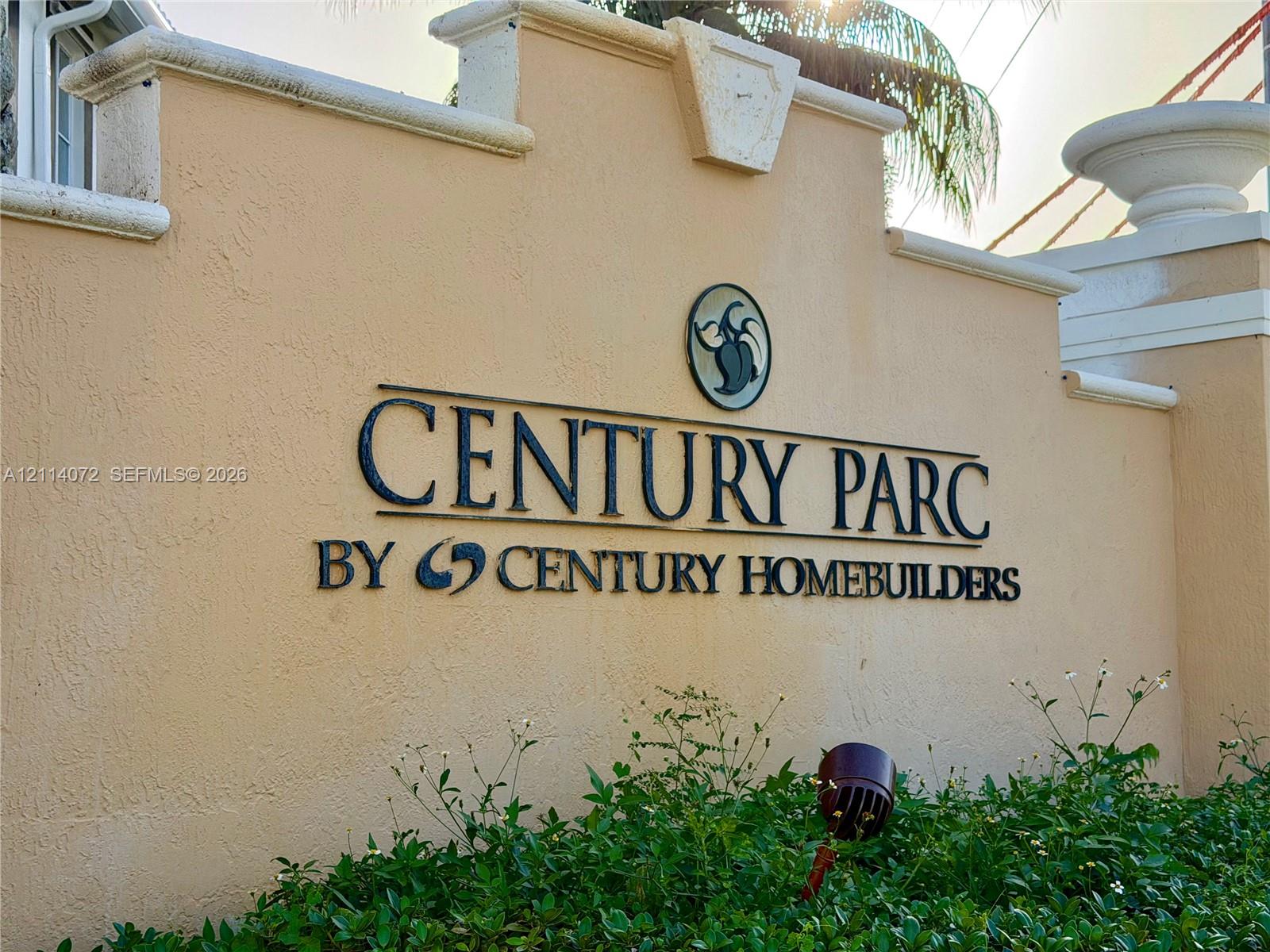 Stucco community monument wall featuring dimensional lettering, decorative masonry caps, and a landscape buffer