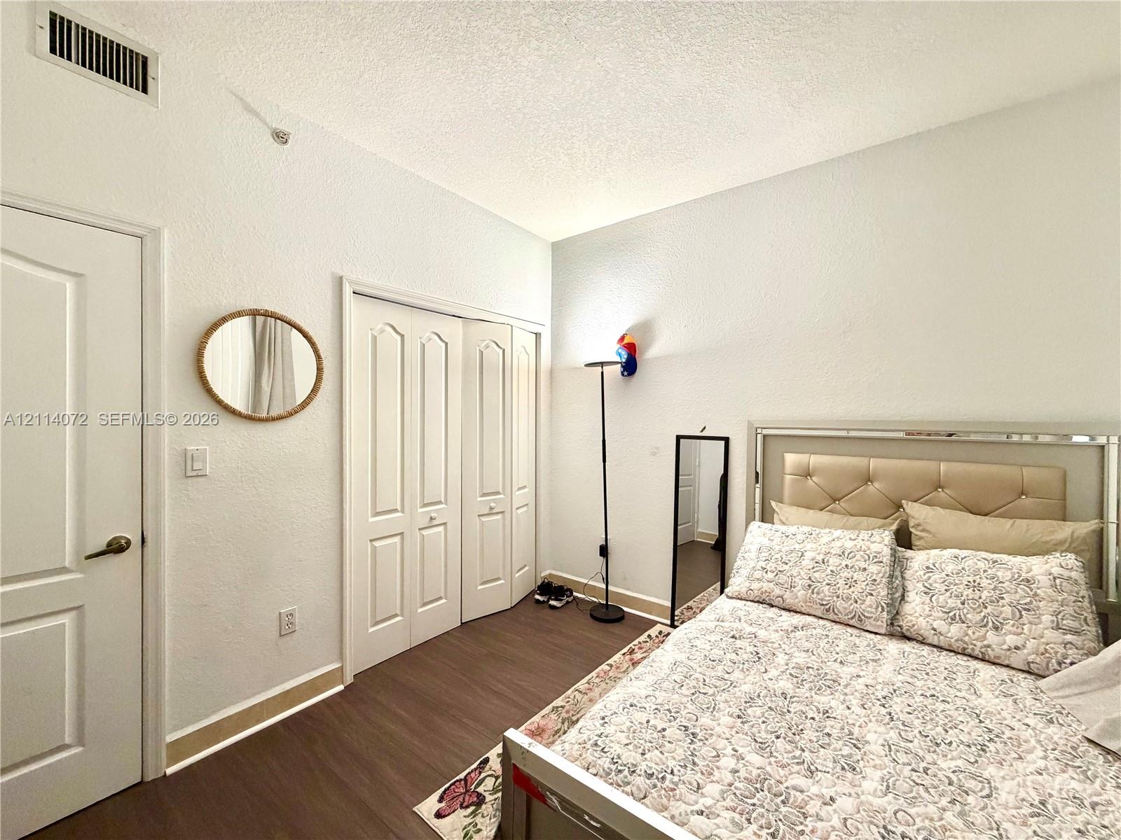 Room featuring wood-finish flooring, textured ceiling, and bi-fold closet doors