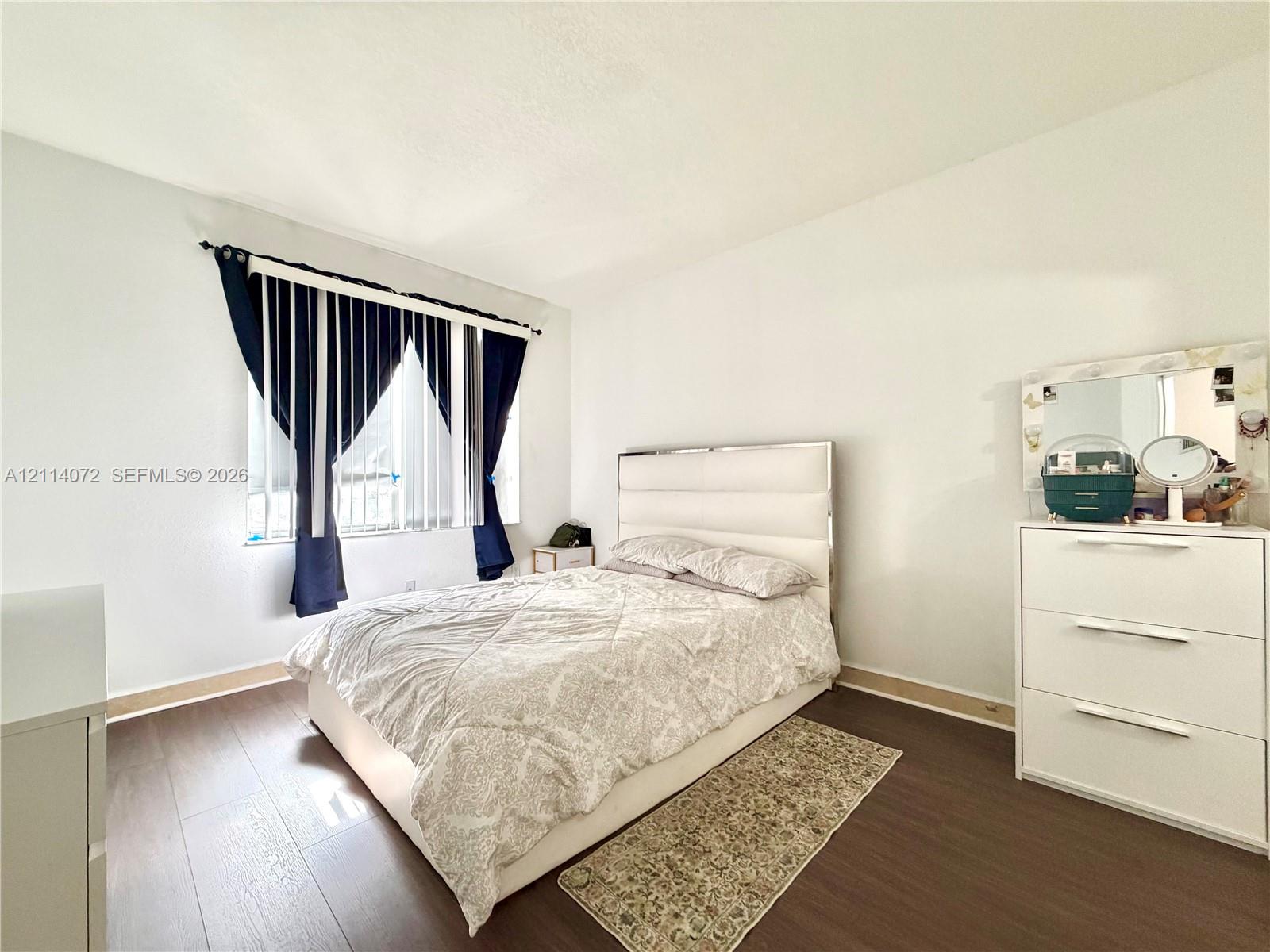 Wood-finish flooring and a single-pane window with vertical blinds
