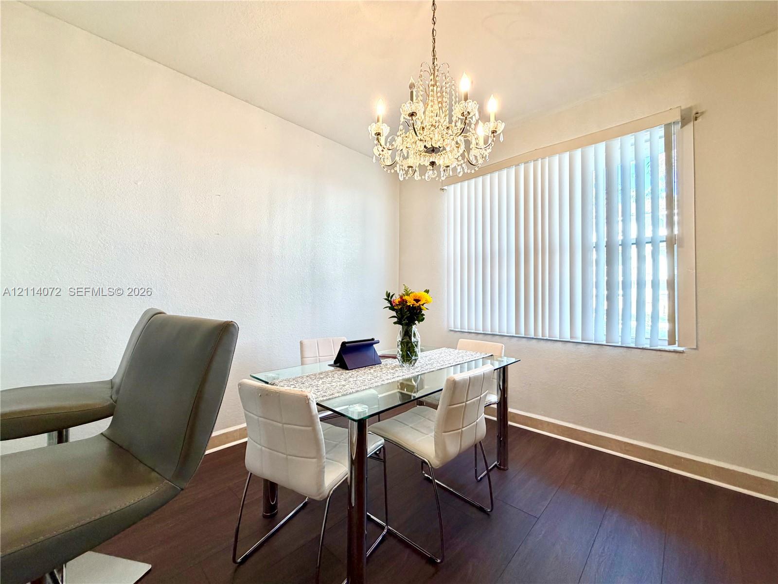 Wood-finish flooring, crystal-style chandelier, and vertical blinds