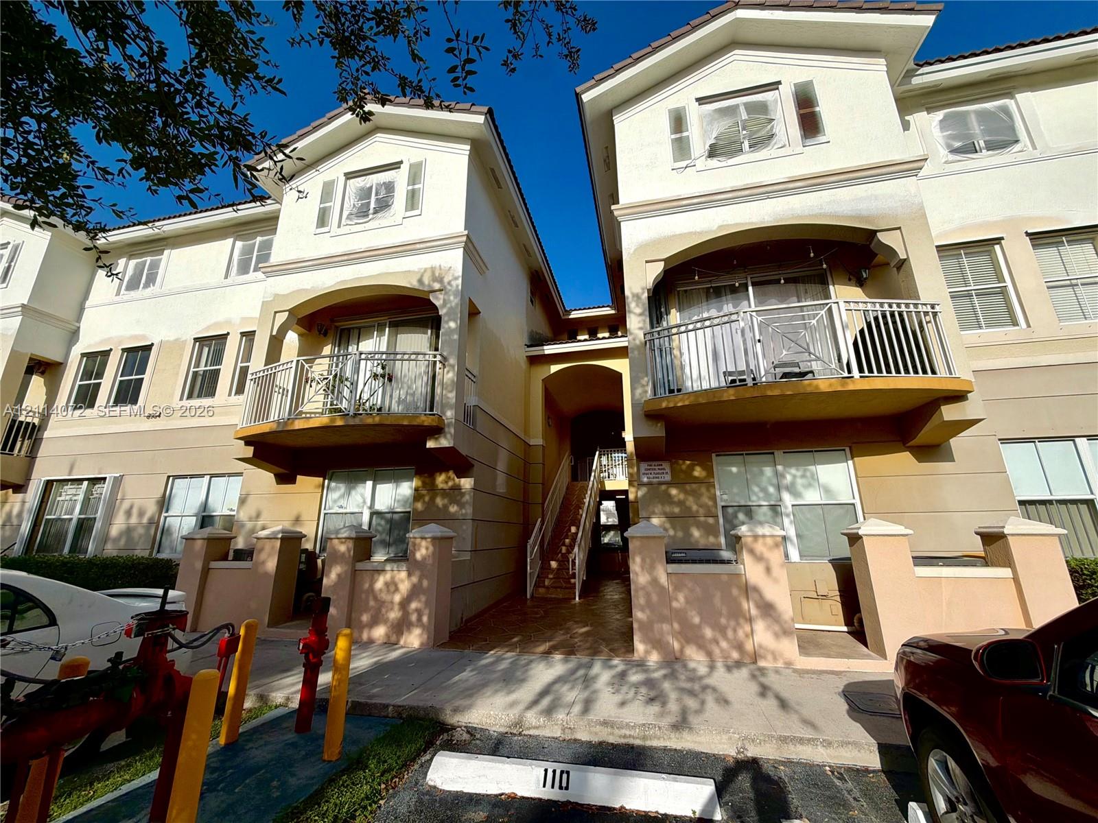 Stucco exterior featuring multi-level balconies with metal railings, arched architectural details, and tiled roofing