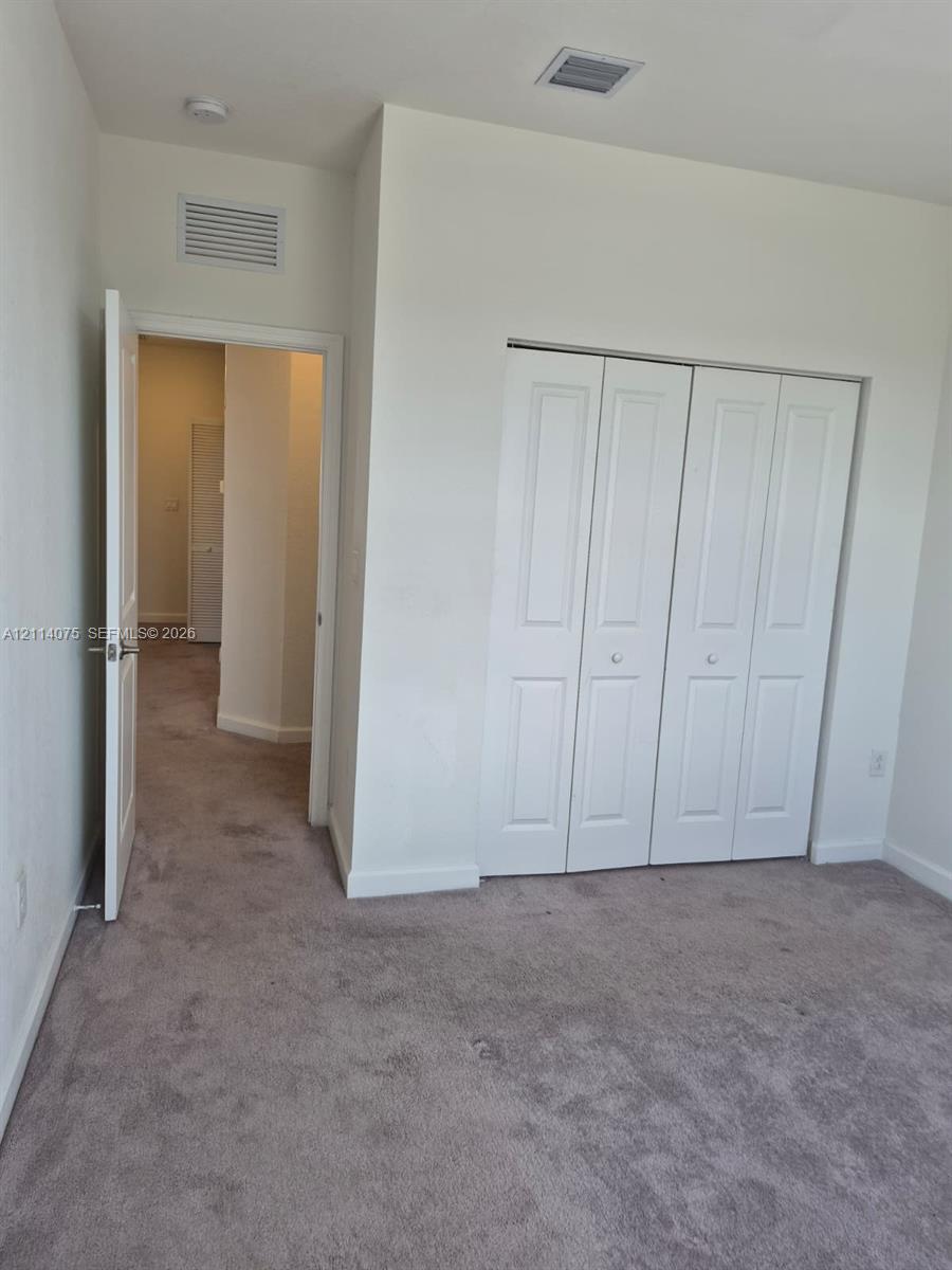 Neutral-toned carpeting throughout with white multi-panel bi-fold closet doors and interior swing door