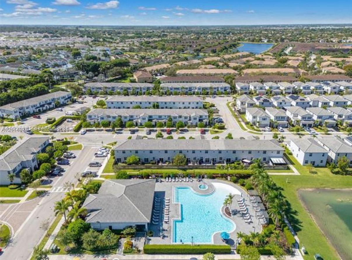 Aerial perspective of community center featuring a swimming pool, integrated spa, paved pool deck, and landscaped green space