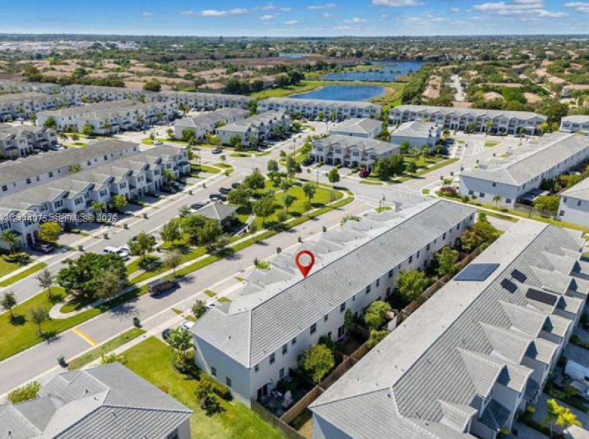 Aerial perspective of a multi-unit residential structure featuring a light-toned exterior, concrete tile roofing, and integrated solar panels