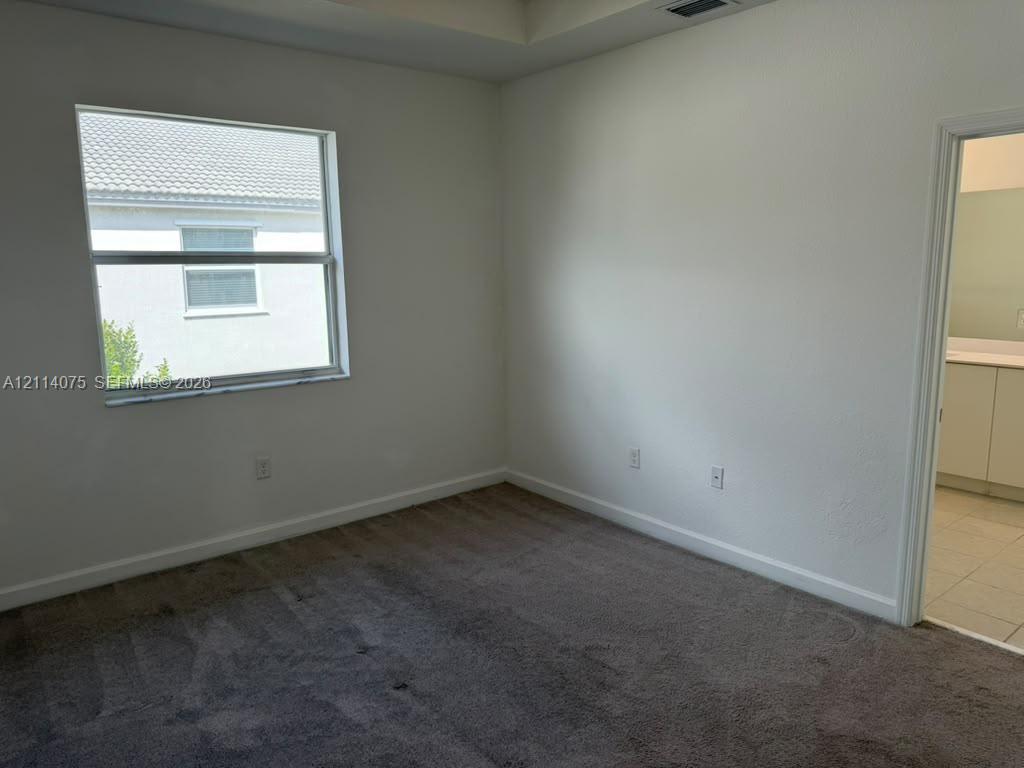 Interior space featuring neutral-toned carpeting, a tray ceiling, and a single-pane window