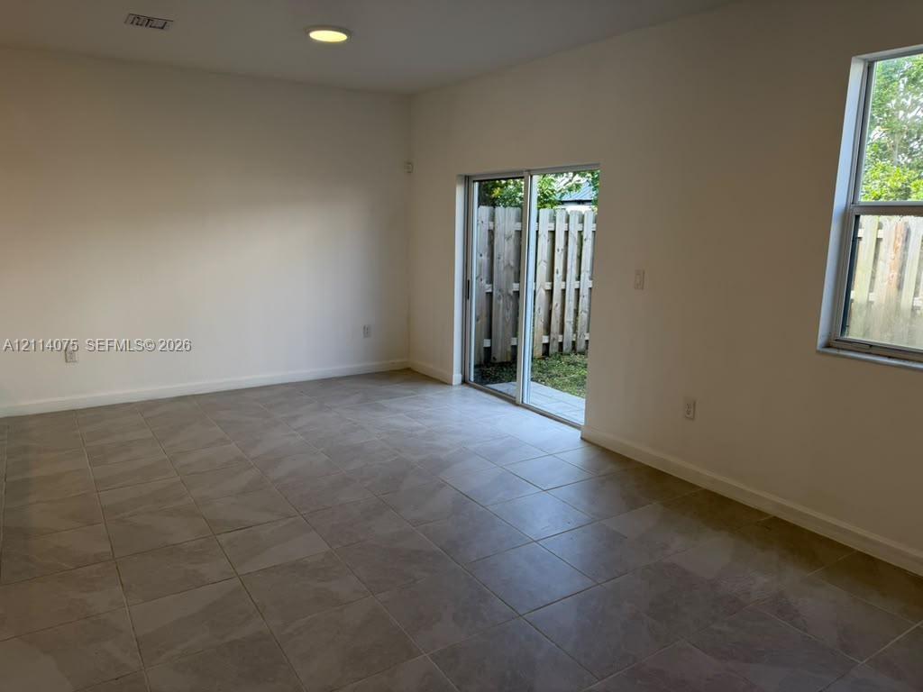 Large-format tile flooring, recessed ceiling lighting, sliding glass door, and vinyl window
