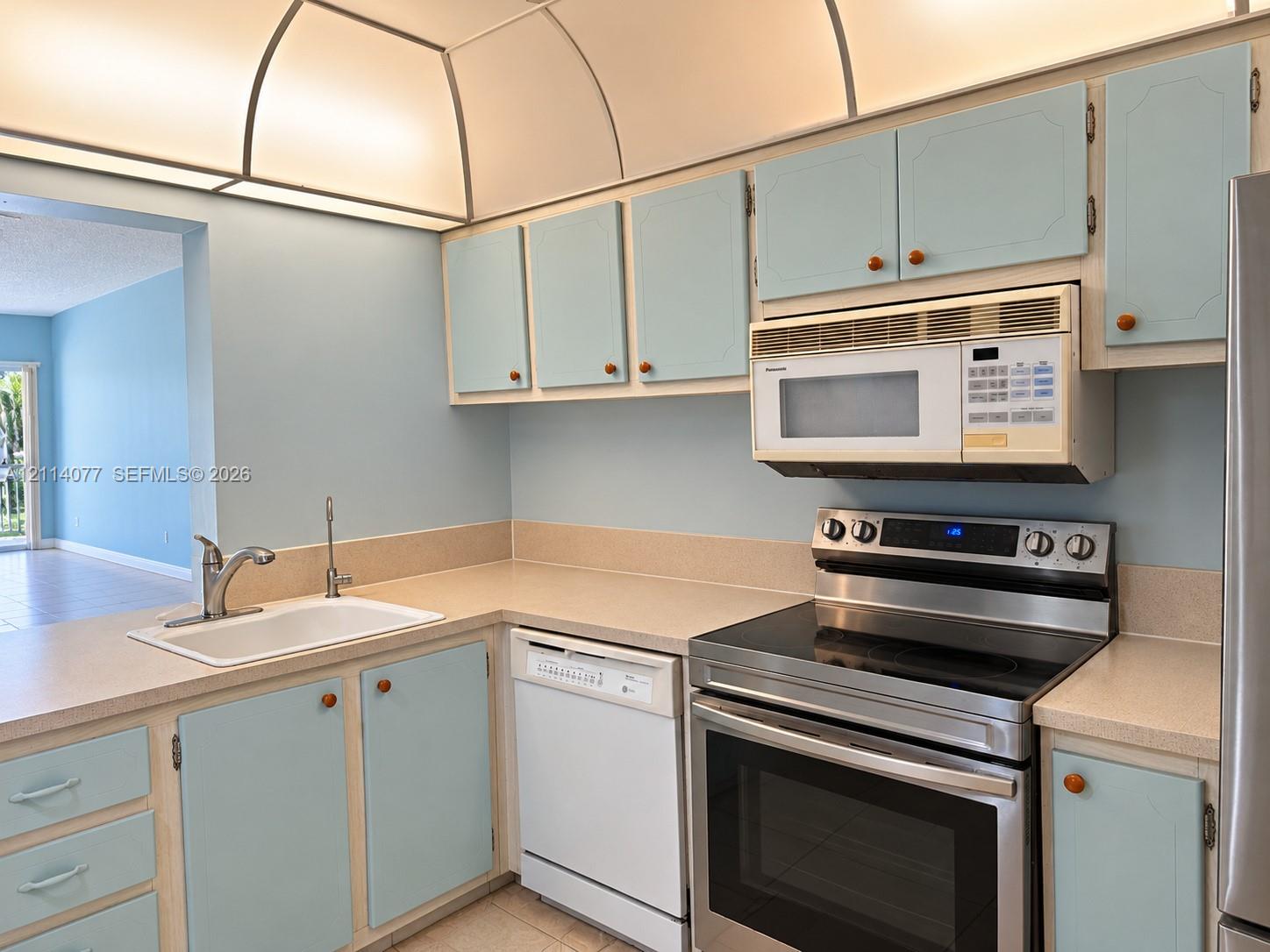 Kitchen featuring built-in cabinetry, solid-surface countertops, integrated cove lighting, and stainless steel appliances