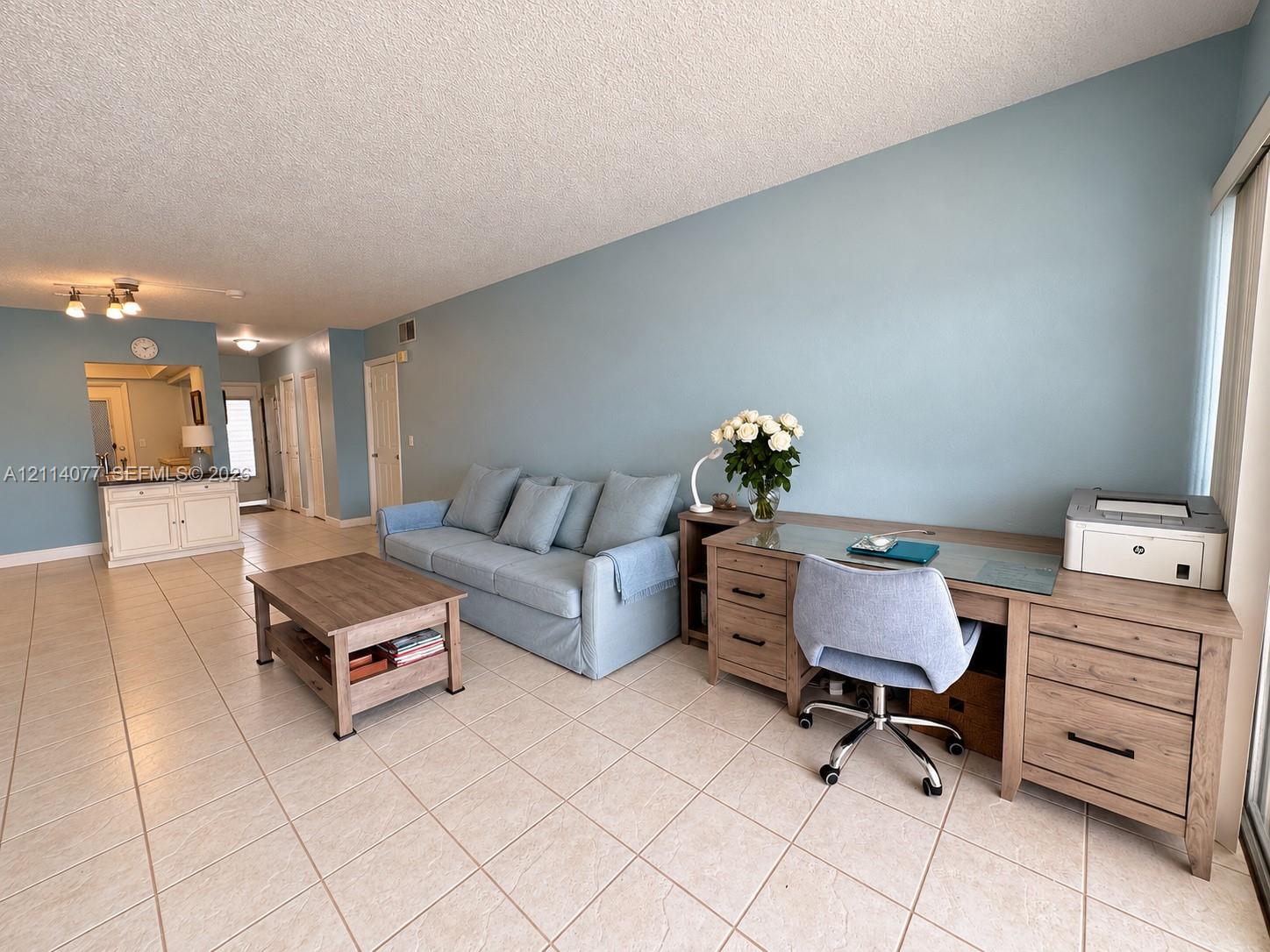 Open-concept living space featuring large-format ceramic tile flooring, neutral wall paint, and a built-in cabinetry unit with a countertop