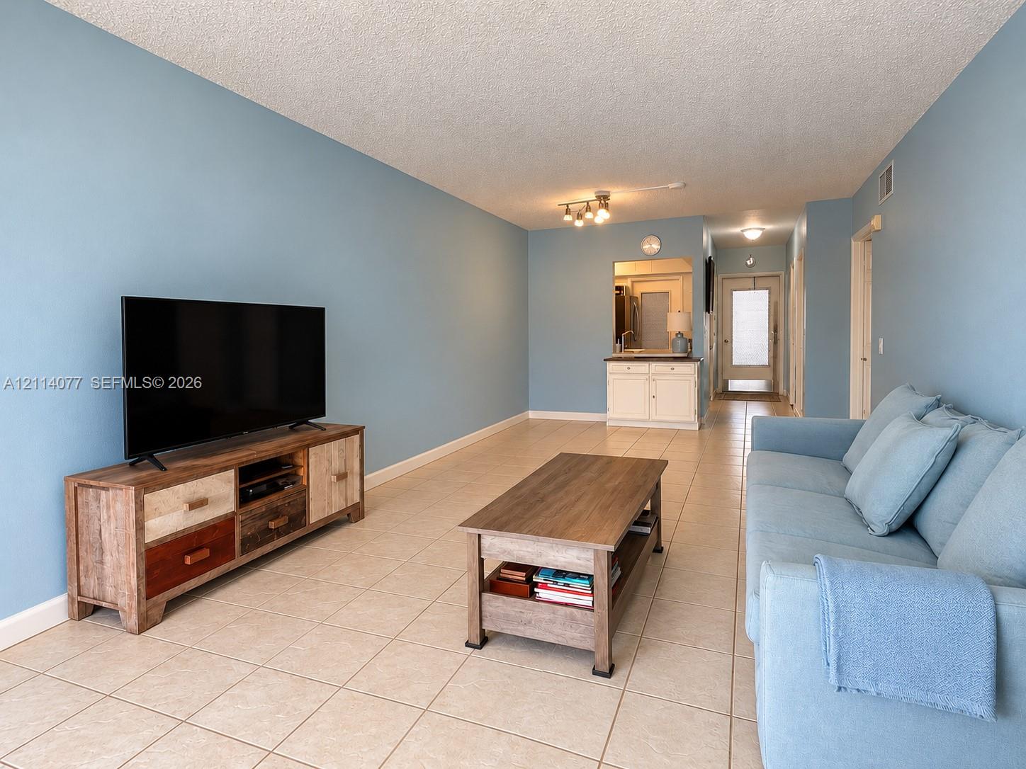 Living space featuring tile flooring, built-in wet bar with cabinetry, and multi-directional track lighting