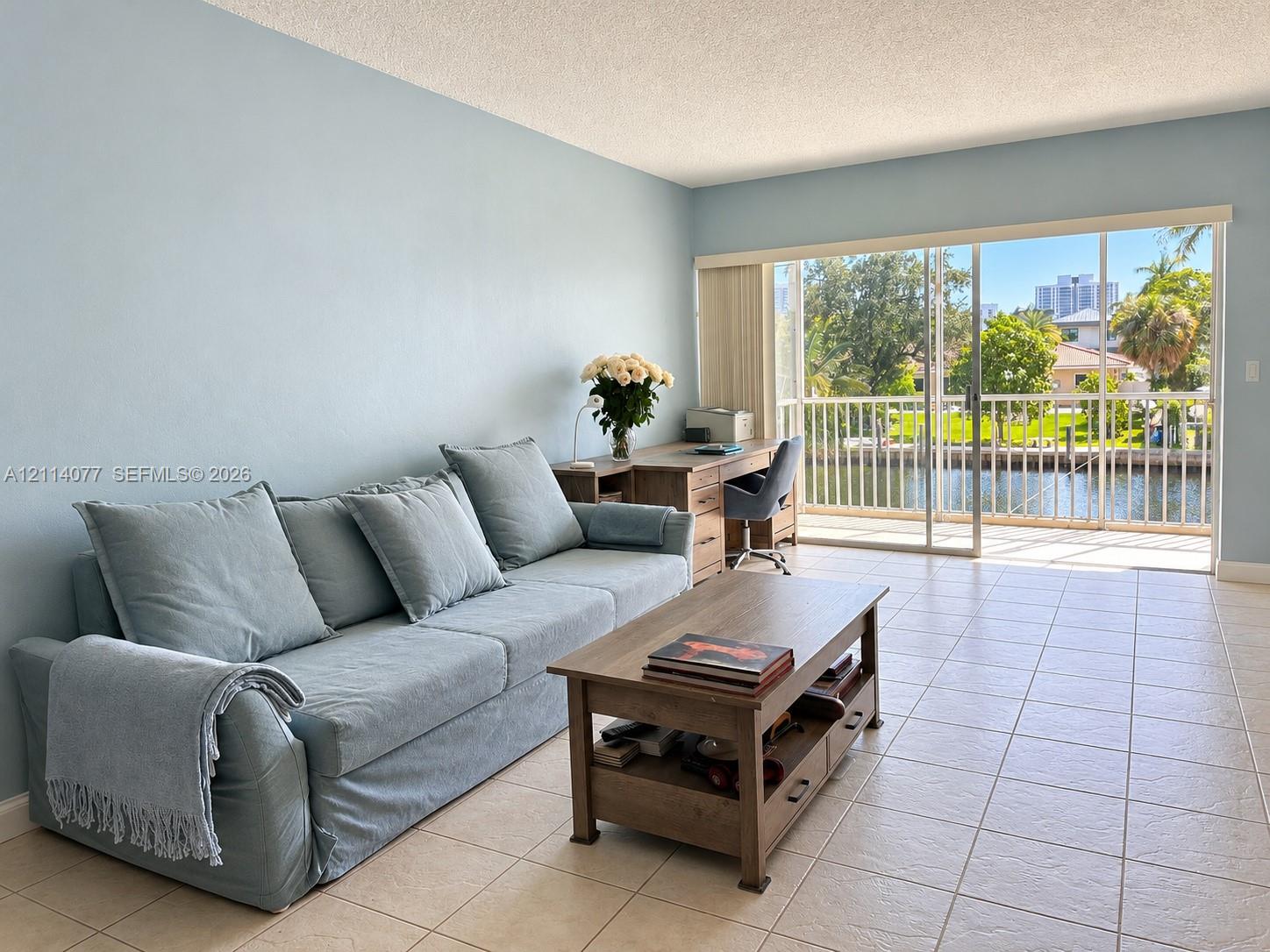 Large-format tile flooring, expansive sliding glass doors, and a private balcony with metal railing overlooking the waterway