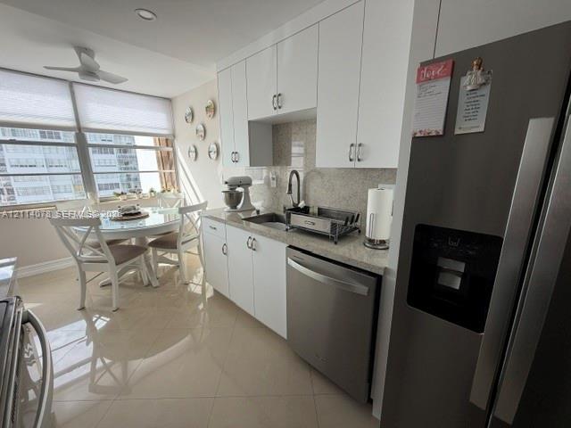 Kitchen featuring white cabinetry, stone-finish countertops, stainless steel appliances, and large-format tile flooring