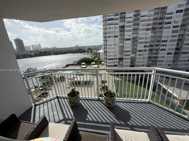 Private covered balcony featuring a white metal railing and concrete flooring