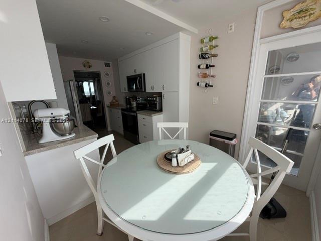 Kitchen featuring white shaker-style cabinetry, solid-surface countertops, recessed lighting, and a multi-lite door with glass inserts