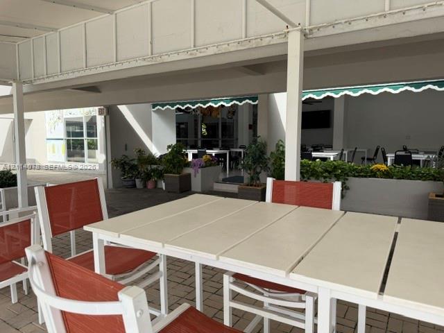 Covered patio featuring a paved stone surface, built-in structural columns, and retractable scalloped awnings