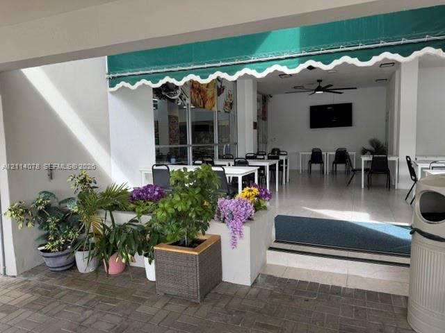 Covered patio featuring a retractable green awning, decorative built-in stone planters, and paver flooring