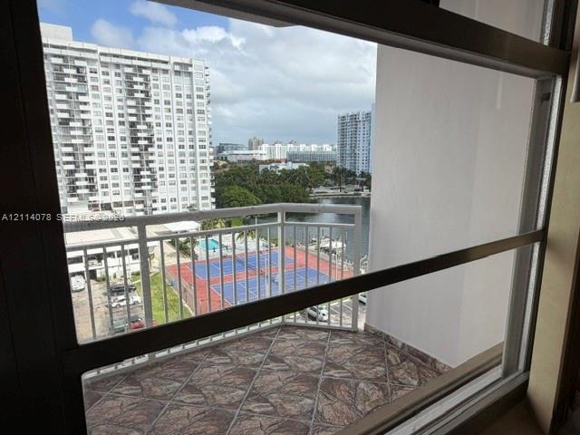 Private balcony featuring flagstone-style tiling and a white metal railing
