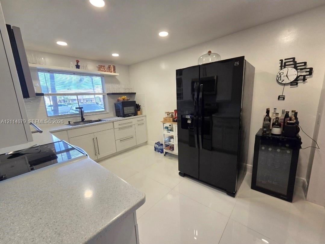Kitchen featuring white cabinetry, solid surface countertops, recessed lighting, and tile flooring Kitchen featuring white cabinetry, solid surface countertops, recessed lighting, and tile flooring