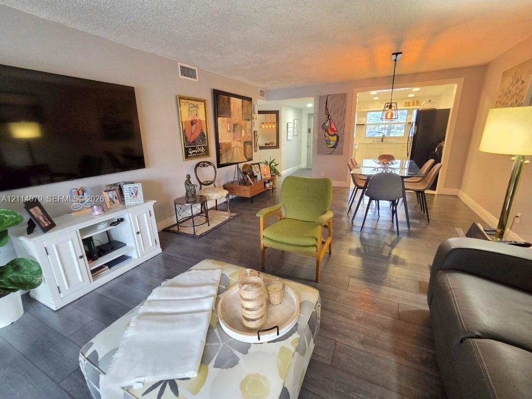 Open concept interior featuring grey wood-finish flooring, recessed lighting, and a modern pendant light fixture Open concept interior featuring grey wood-finish flooring, recessed lighting, and a modern pendant light fixture