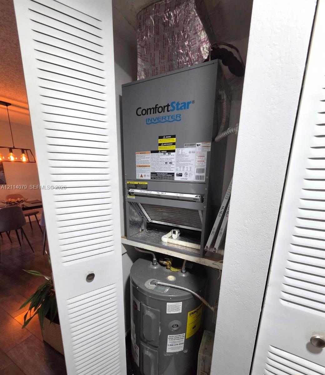 Utility closet housing a ComfortStar inverter HVAC system and water heater, enclosed by dual white louvered doors