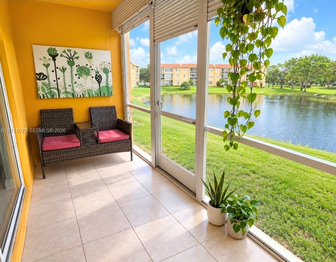 Screened-in porch featuring large-format tile flooring, expansive floor-to-ceiling windows, and direct water exposure