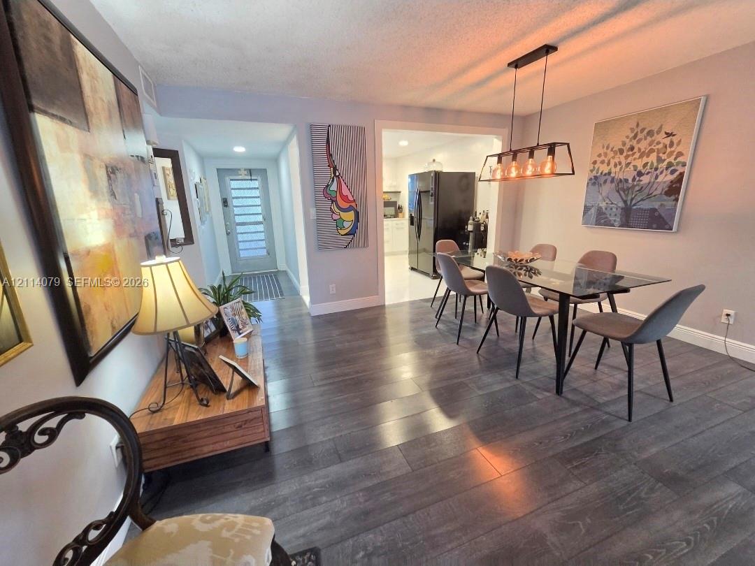 Wood-finish flooring, rectangular multi-light pendant fixture, and glass-paneled entry door