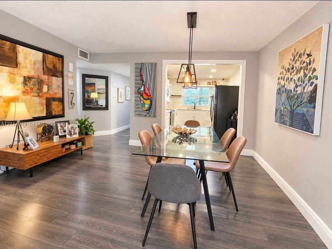 Dining area featuring wood-finish flooring, a geometric pendant light fixture, and neutral wall tones Dining area featuring wood-finish flooring, a geometric pendant light fixture, and neutral wall tones