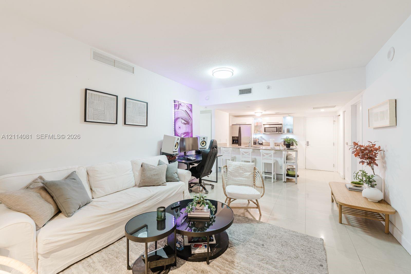 Living area featuring large-format tile flooring, recessed lighting, and a kitchen peninsula with integrated seating