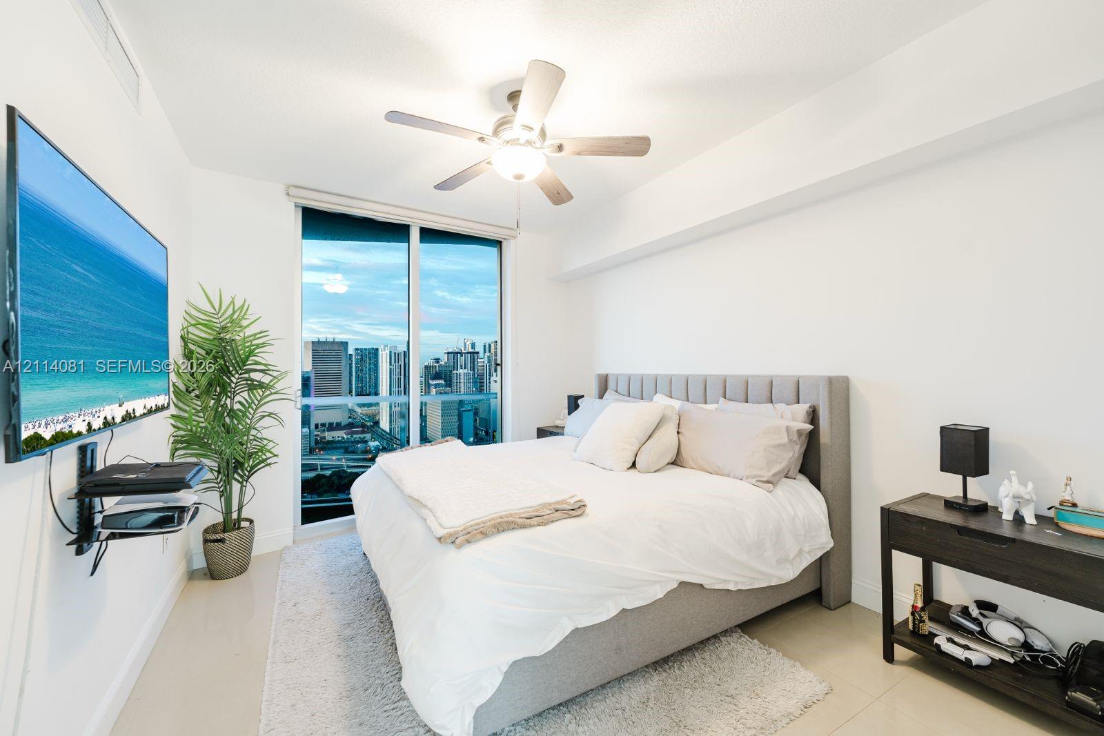 Floor-to-ceiling glass sliding doors, neutral tile flooring, and a ceiling-mounted light fixture with integrated fan