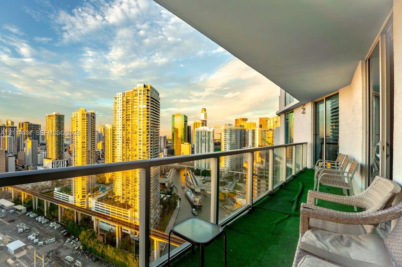 Covered balcony with glass and metal railings, showcasing an urban cityscape