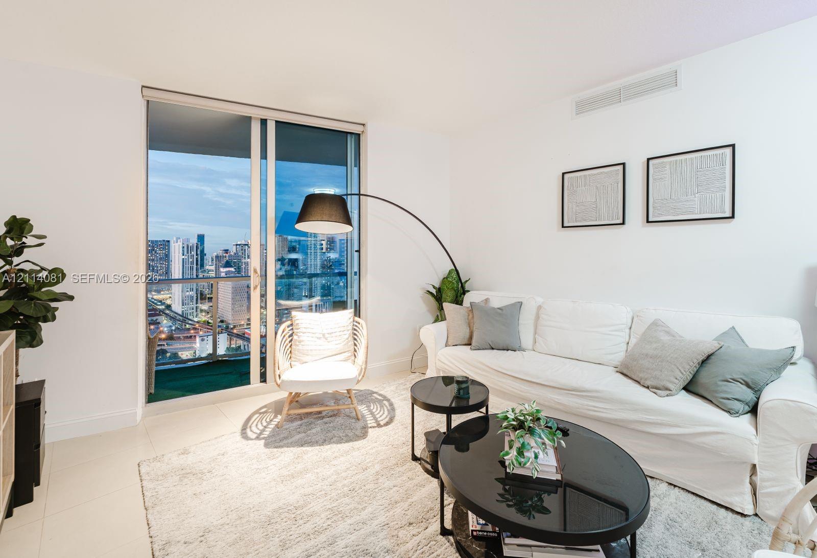 Full-height sliding glass door, neutral floor tiles, and urban skyline backdrop
