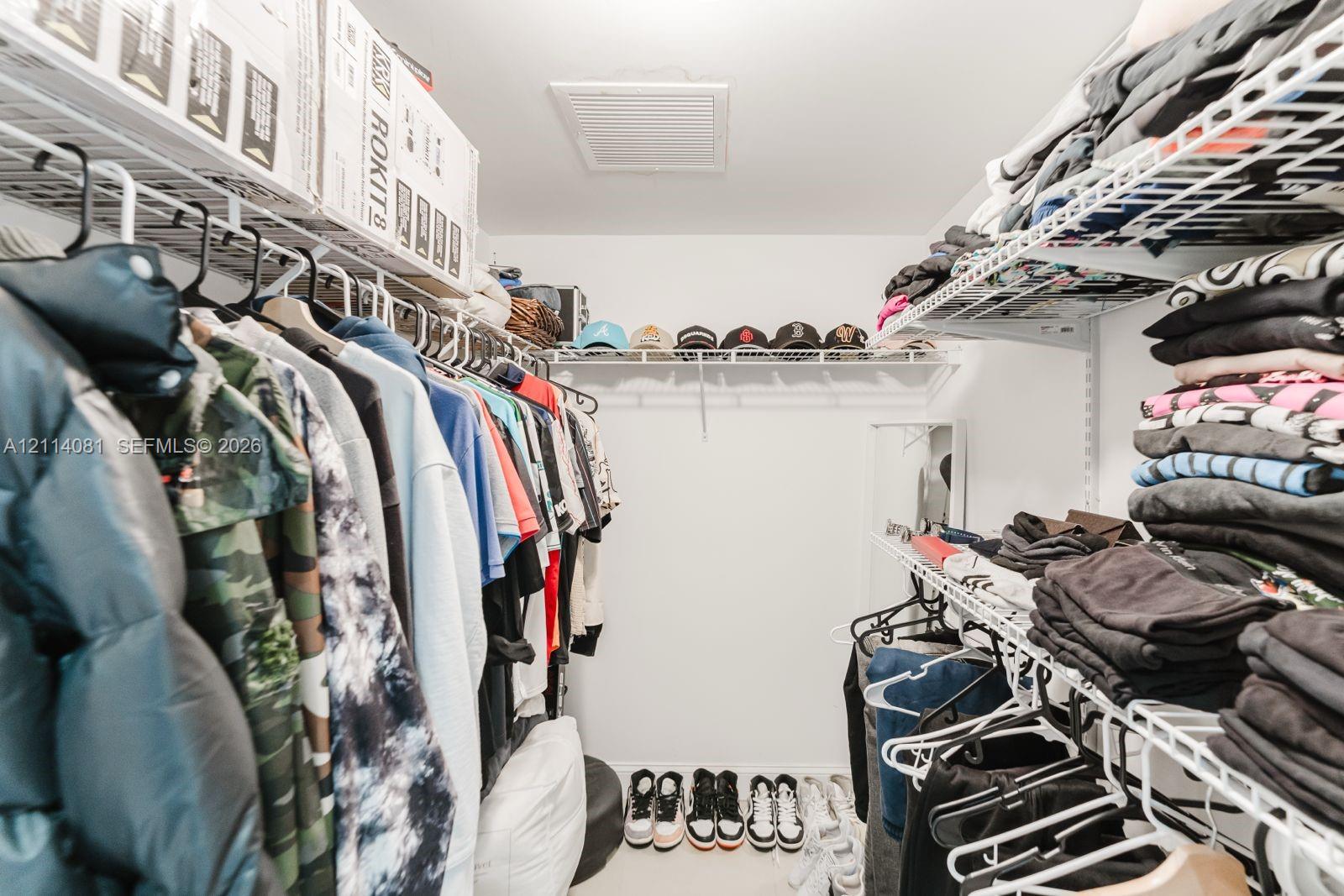 Walk-in closet featuring tiered white wire shelving and a multi-level storage configuration