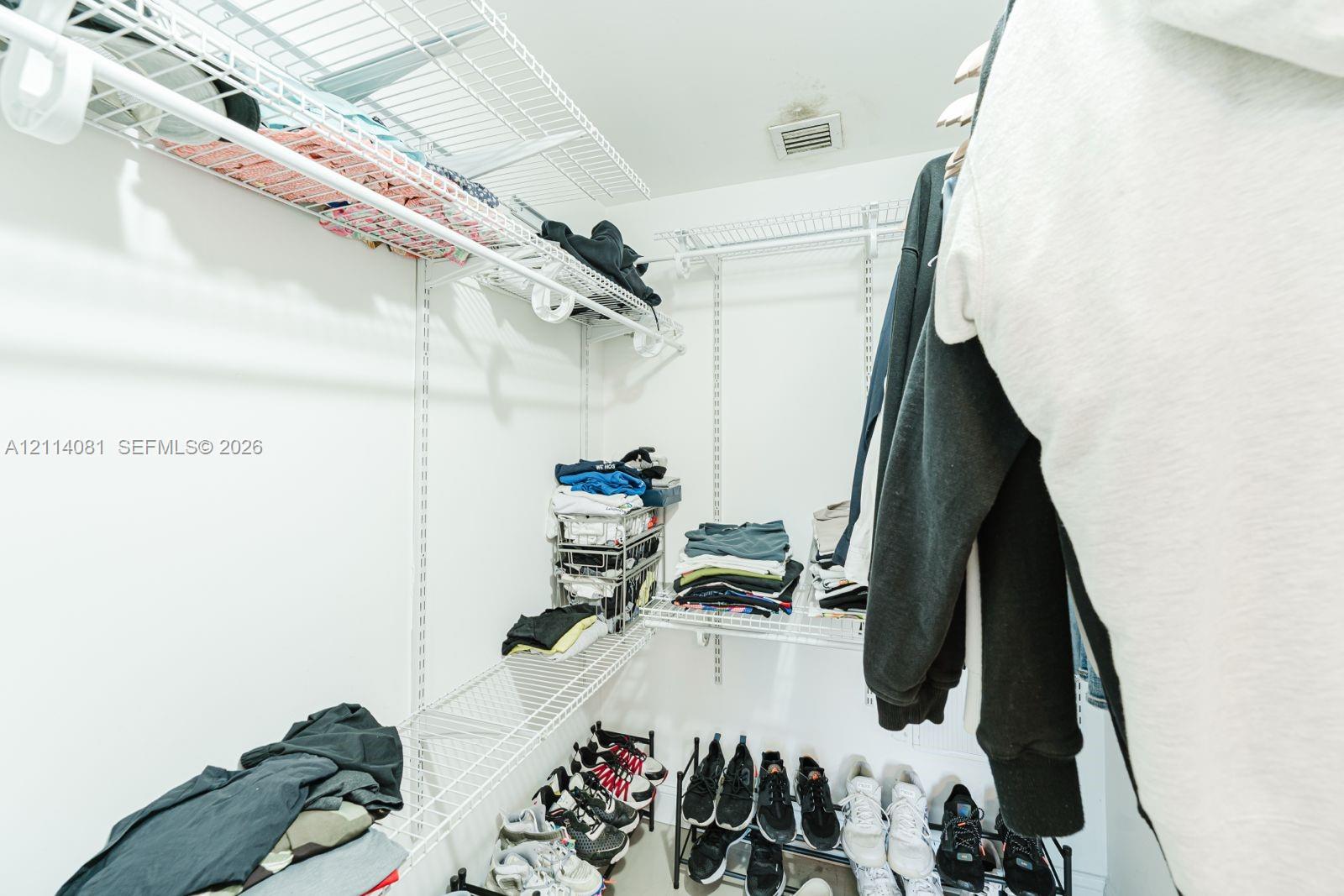 Walk-in storage space featuring white wire shelving units and integrated wall-mounted tracks