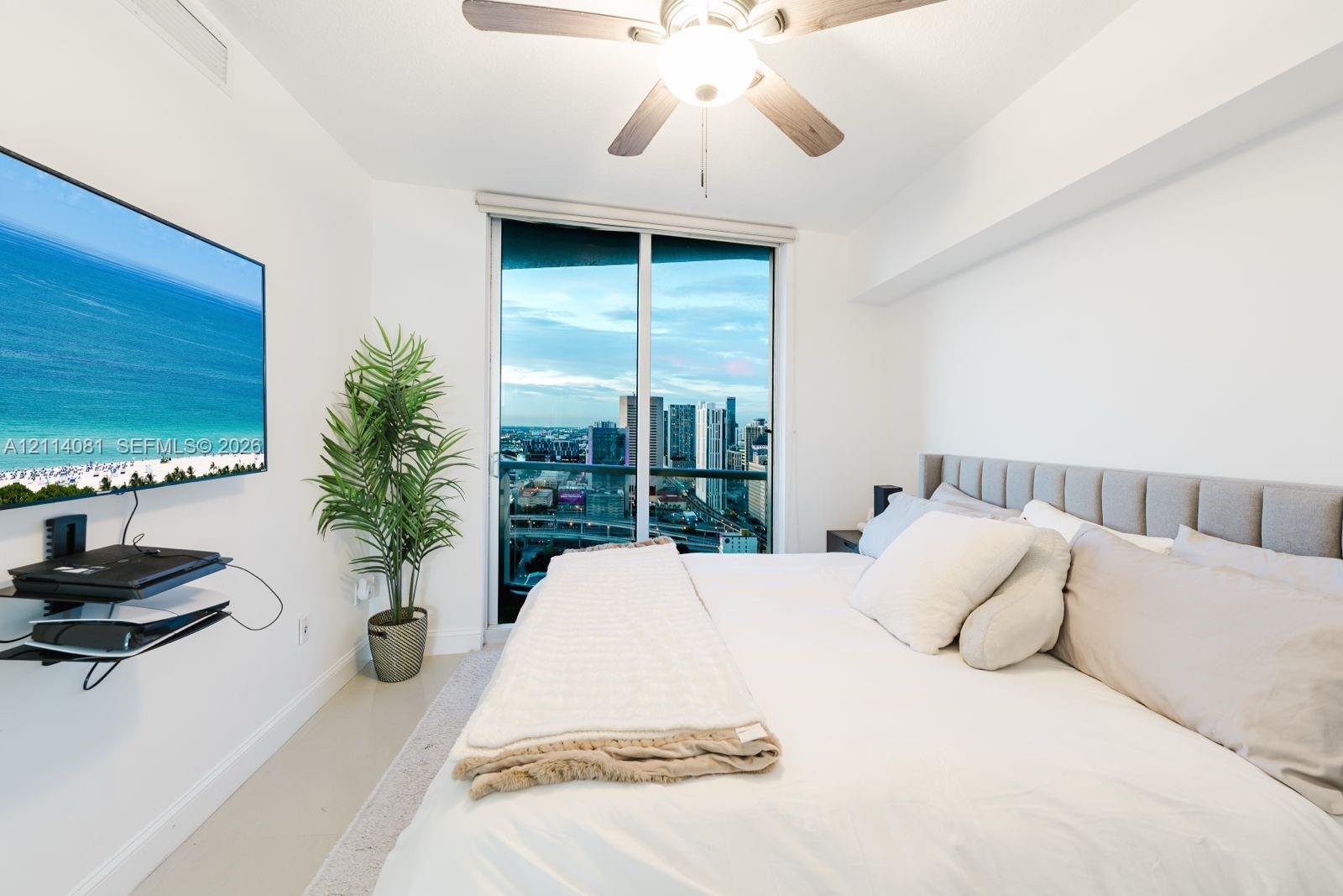 Floor-to-ceiling sliding glass door, ceiling fan with integrated lighting, and neutral-toned wall-to-wall flooring