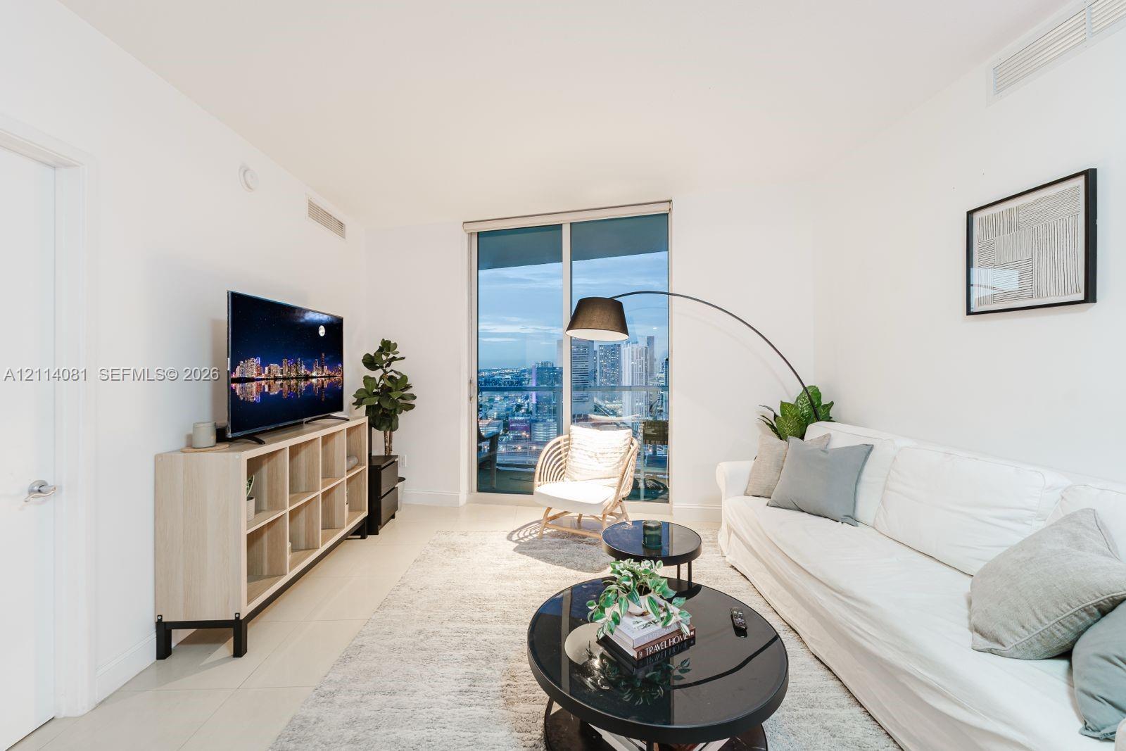Floor-to-ceiling glass sliding door, neutral tiled flooring, and high-rise cityscape horizon